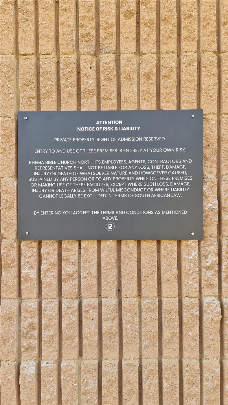 Printed notice plaque mounted on a brick wall